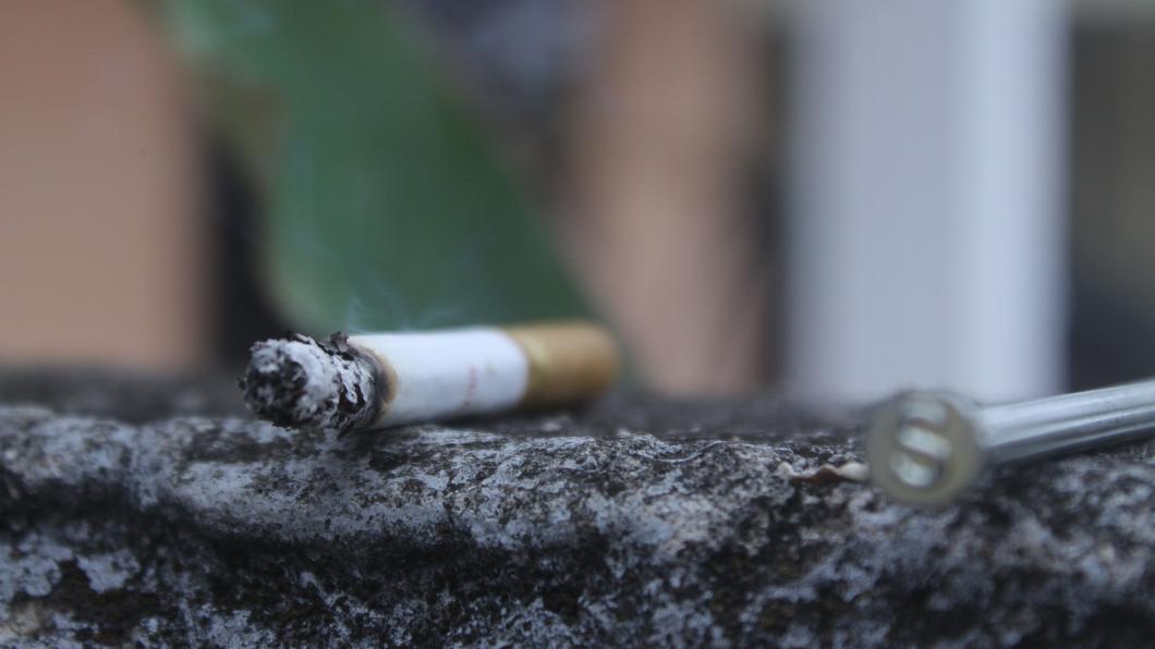 Een foto van een smeulende sigaret op de grond